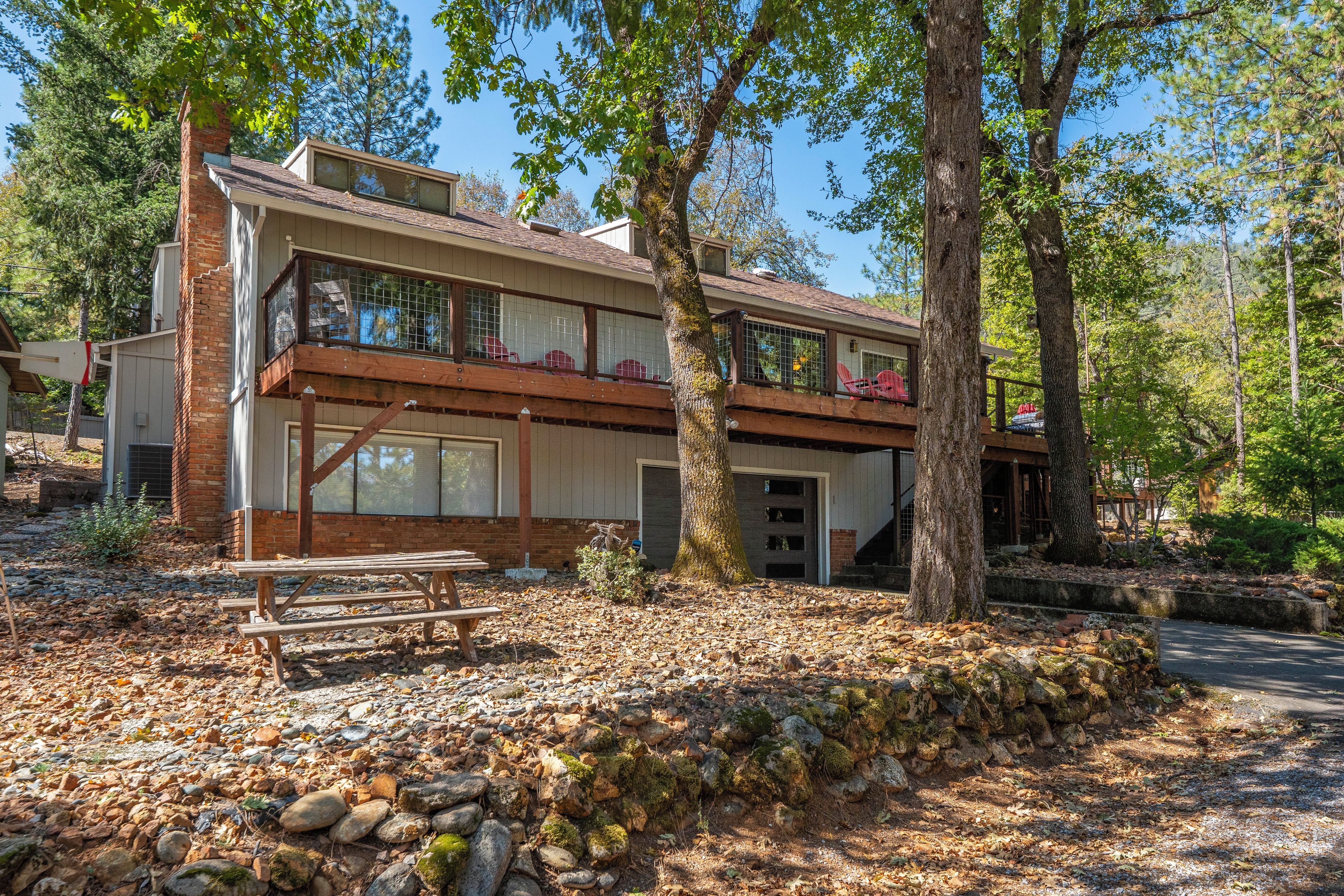 A two-story house with a balcony, a covered patio, and a stone wall.