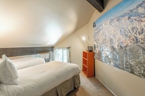 A bedroom with two beds, a desk, a chair, a map on the wall, and a window with curtains. - Steps to Shuttle | Communal Amenities (Mammoth Lakes)