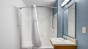 A bathroom with a shower, a sink, and a mirror. - Value Place Wichita Ks West (Wichita)