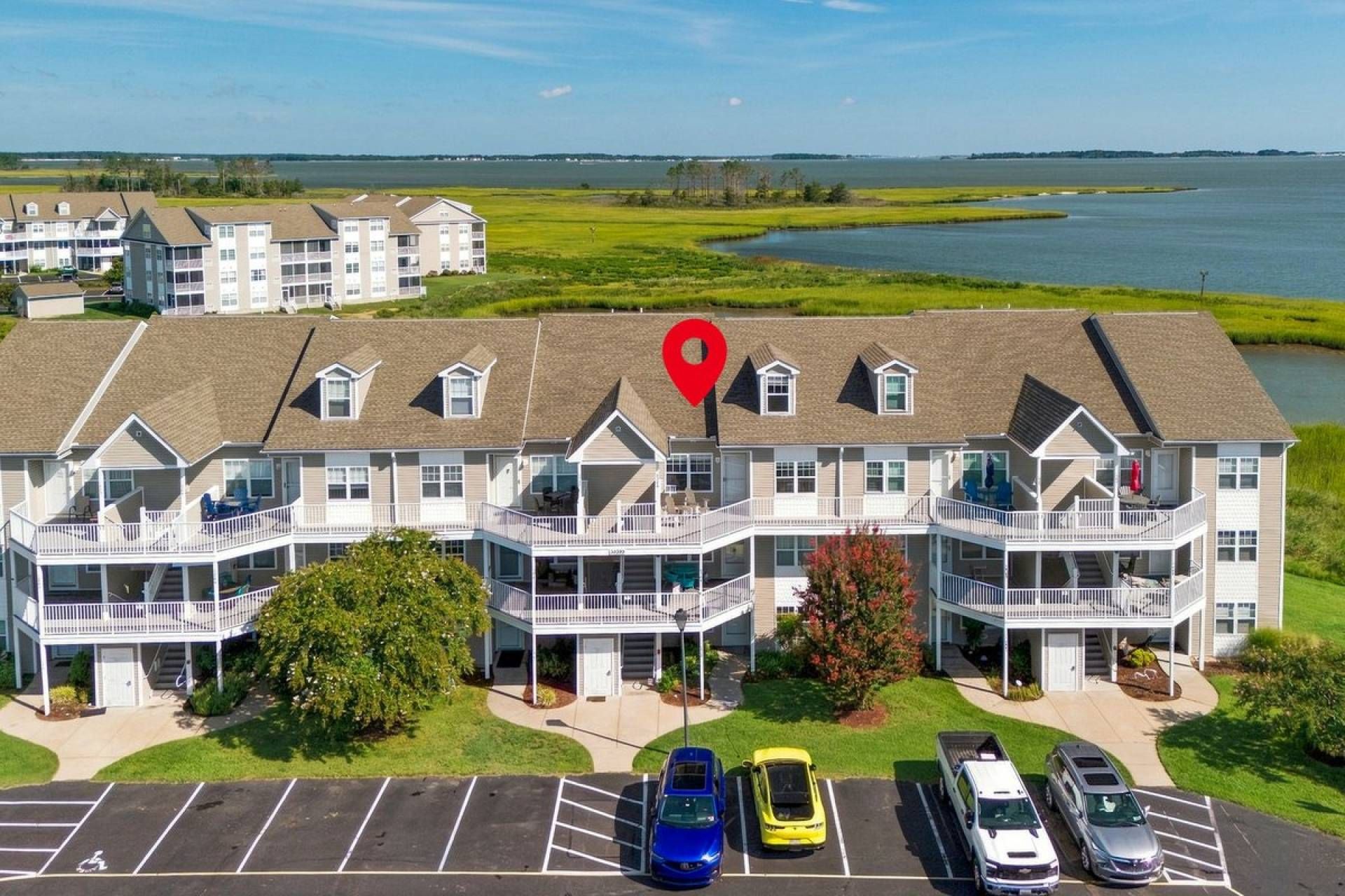 Un hotel de varios pisos con balcones, estacionamiento y vistas al lago.