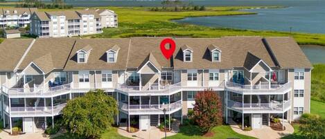 A multi-story hotel with balconies, parking lot, and a view of a lake.