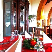 Un comedor con mantel rojo, cristalería y un centro de mesa con velas.