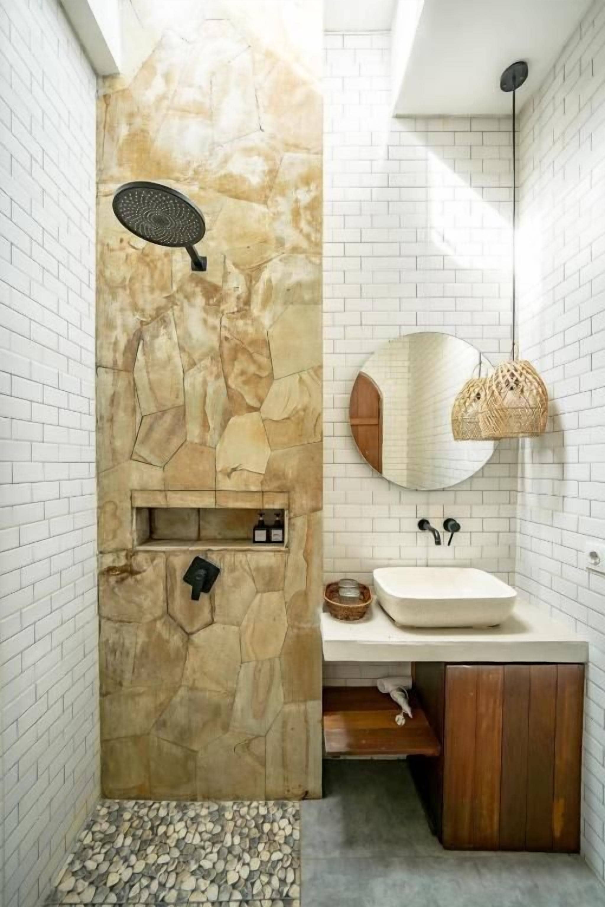 A bathroom with a stone wall, a white sink, and a mirror.