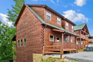 A two-story log cabin with a porch and a balcony. - Luxury Lodge w/ Pool, Game Room & Mountain Views (Sevierville)