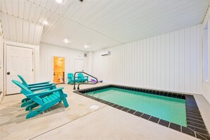 An indoor swimming pool with a tiled edge, a ceiling with recessed lighting, and two green Adirondack chairs. - Luxury Lodge w/ Pool, Game Room & Mountain Views (Sevierville)