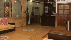 Un área de recepción con un sofá, un mostrador y una pared decorativa con una estatua.