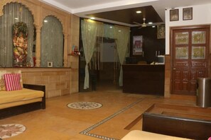 Un área de recepción con un sofá, un mostrador y una pared decorativa con una estatua.