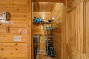 Een houten interieur met een telefoon, planken met diverse voorwerpen, en een metalen rek met dozen.