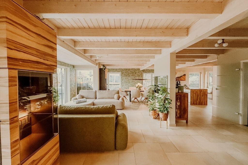 A spacious living area with a wooden ceiling, a sofa, a dining table, and a kitchen area.