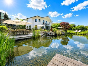 A modern house with a pool, outdoor furniture, and lush greenery.
