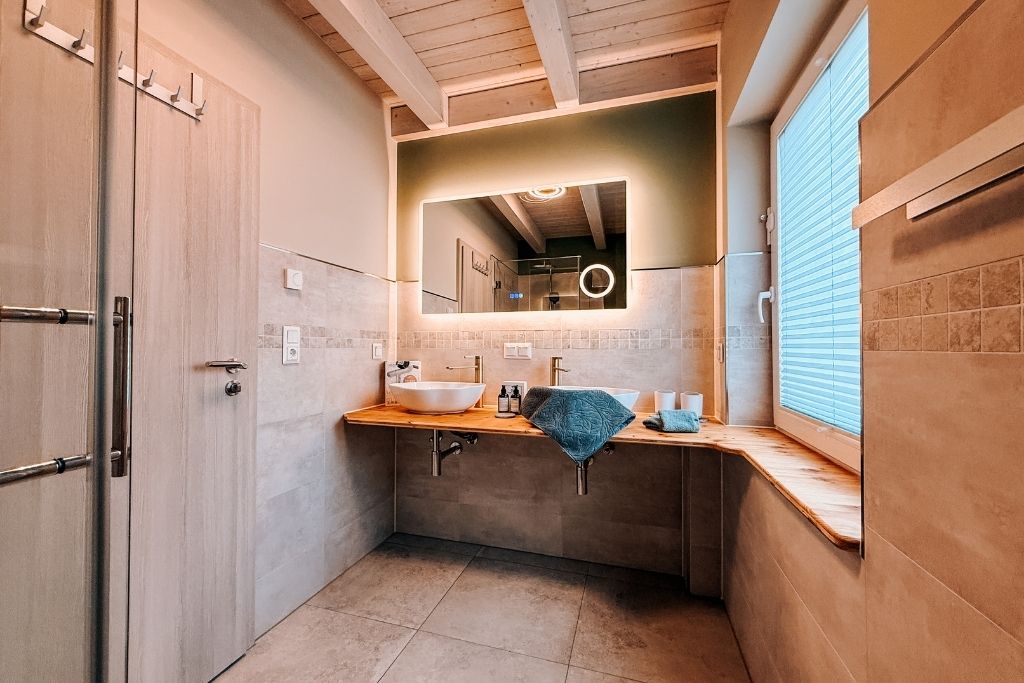 Une salle de bain avec un grand miroir, un lavabo et un porte-serviettes.