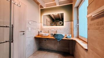 Une salle de bain avec un grand miroir, un lavabo et un porte-serviettes.
