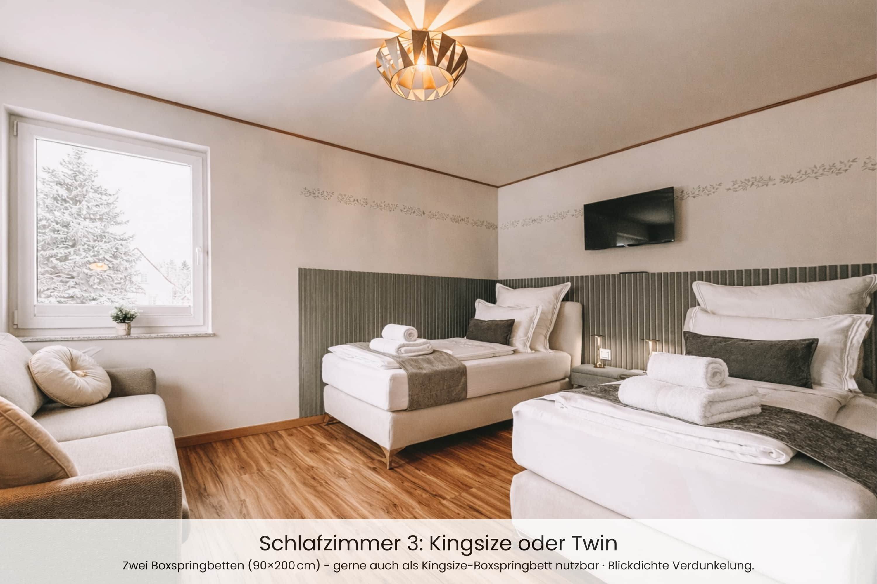 Un dormitorio con una cama tamaño king y una cama individual, ambas con toallas ordenadamente dobladas.