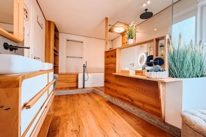Une salle de bain moderne avec un plancher en bois, un grand miroir et un lavabo.