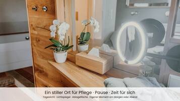 A wooden vanity with a mirror, a tissue box, and two potted plants.