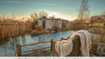 Una terraza con vista a la naturaleza, que incluye un cuerpo de agua y vegetación circundante.