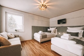 Une chambre d’hôtel moderne équipée d  ’un lit, d’un canapé, d’une télévision et d’une fenêtre donnant sur un arbre.