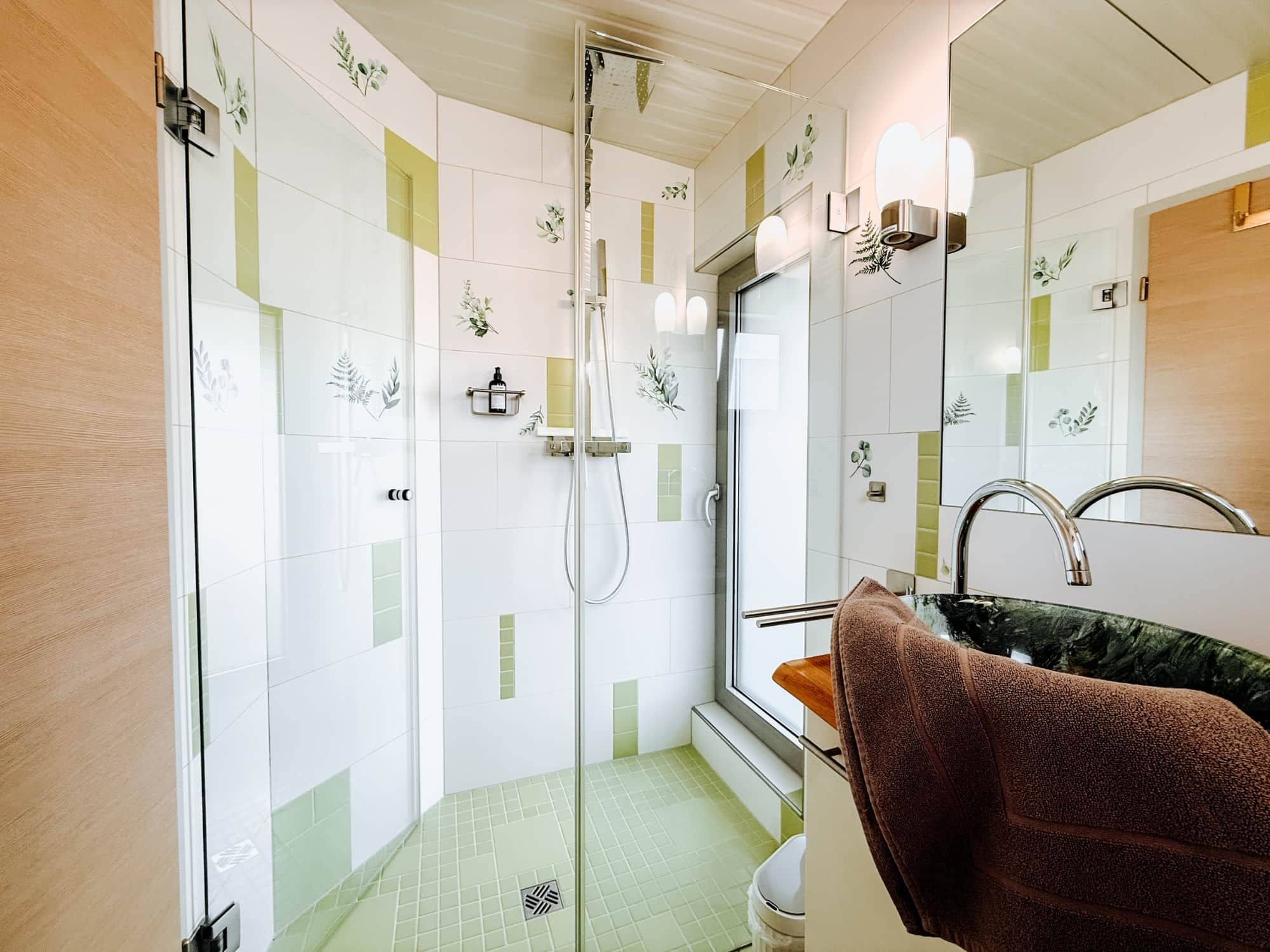 Ein modernes Badezimmer mit Duschkabine aus Glas, Waschbecken mit Marmorplatte und Handtuchhalter.