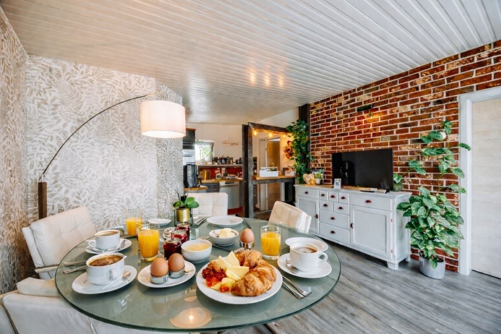 Ein Frühstückstisch mit Glasplatte, weißen Stühlen und einer Ziegelwand.