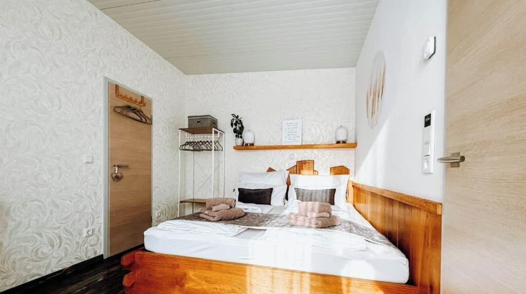 Une chambre à coucher avec un lit en bois, une table de chevet, une étagère fixée au mur et une porte.