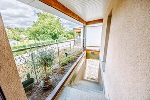 A balcony with a view of a garden and a street.