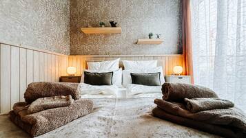 Ein Schlafzimmer mit einem großen Bett, zwei Nachttischen, einem Holzkopfstück und einem Fenster mit Vorhängen.