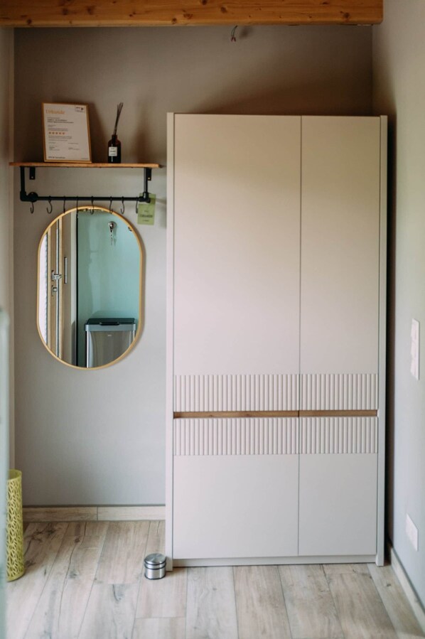 A room with a wardrobe, a mirror, and a shelf with a certificate.