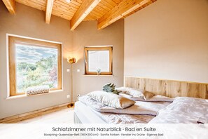 A bedroom with a large window, a bedside lamp, and a view of greenery outside.