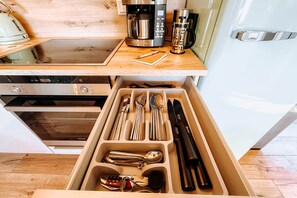 A kitchen with a wooden countertop, a coffee maker, and a drawer organizer with utensils. - Sternenzauber Wellness Apartment (Großpösna)