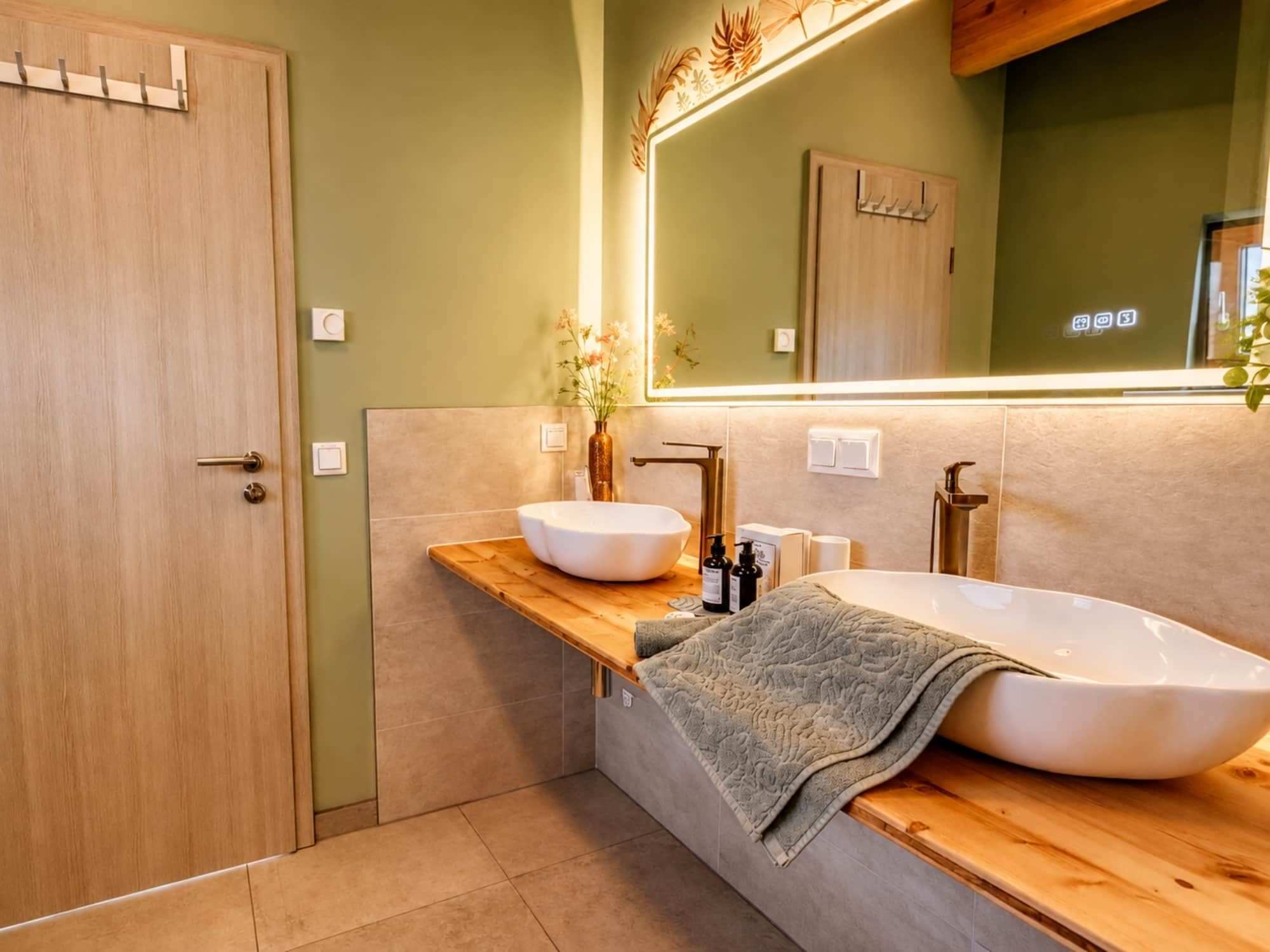 Ein Badezimmer mit einem Holzkosmetikschrank, einem großen Spiegel und einem weißen Waschbecken.