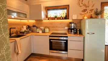Een moderne keuken met een inbouwoven, een koffiezetapparaat en een koelkast.