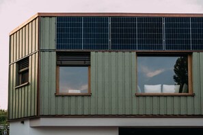 A modern building with a flat roof, large windows, and solar panels.