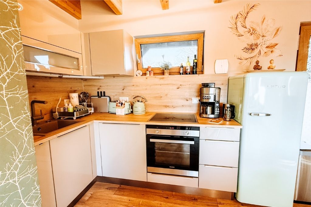 A modern kitchen with white cabinetry, a wooden countertop, a built-in oven, and a refrigerator.