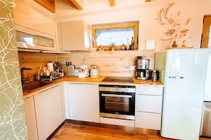 A modern kitchen with white cabinetry, a wooden countertop, a built-in oven, and a refrigerator.