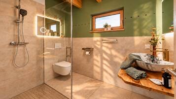 Ein modernes Badezimmer mit Duschkabine aus Glas, Toilette und Waschtisch mit Marmorbecken.