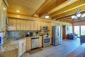 A spacious kitchen with wooden cabinets, stainless steel appliances, and a granite countertop. - Luxurious Mountain Retreat w/ Theater & Indoor Pool (Sevierville)