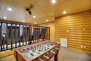 Ein Zimmer mit Holzboden, einem Tischfußballspiel und einer Projektionsleinwand.