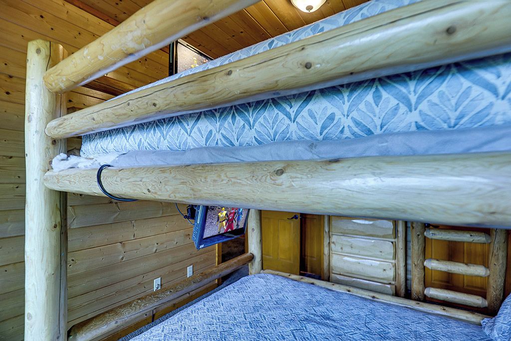 Ein Stockbett mit gemustertem Lattenrost, Holzwänden und einem kleinen Fenster.