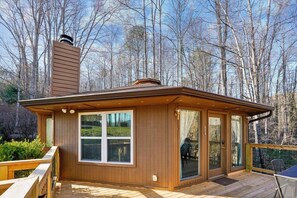 A wooden cabin with a deck, large windows, and a chimney. - Charming Retreat w/ Hot Tub in Gatlinburg (Gatlinburg)