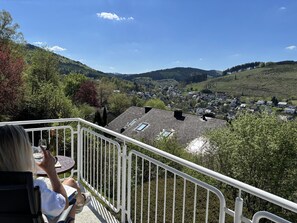 Ein Balkon mit Blick auf ein Dorf und Hügel.