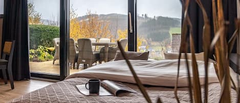 Un dormitorio con una cama grande, una taza de café y vistas a un patio exterior con sillas y una mesa.