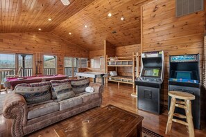 Ein Ferienhaus-Interieur mit Billardtisch, Sofa und Spielautomaten.