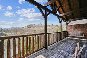 A wooden deck with a railing overlooking a hilly landscape. - 3-Bedroom Cabin w/ Game Room & Hot Tub (Gatlinburg)