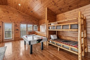 A wooden cabin interior with a pool table, bunk beds, and a windowed door. - 3-Bedroom Cabin w/ Game Room & Hot Tub (Gatlinburg)