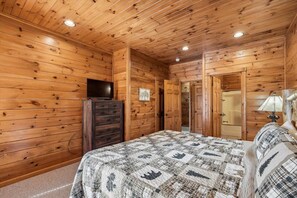 Ein Zimmer mit Holzvertäfelung, einem Bett, einem Schminktisch und einem Fernseher an der Wand.