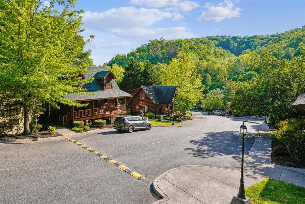 A residential area with a house featuring a porch, a driveway, and a car parked in front.