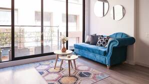 A modern living room with a blue sofa, two round mirrors, a small table with a vase, and a geometric rug. - Studio in Unicentro|Santa Barbara|Clinica Santafe (Bogotá)