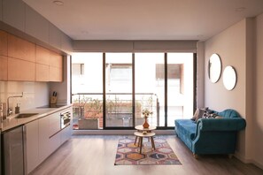 A modern apartment with a kitchen, a sofa, and a balcony with a view. - Studio in Unicentro|Santa Barbara|Clinica Santafe (Bogotá)