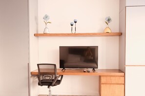 A modern office space with a desk, chair, television, and decorative items on shelves. - Studio in Unicentro|Santa Barbara|Clinica Santafe (Bogotá)