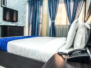 A hotel room with a bed, a bedside telephone, and a television on the wall. - Nanet Suites (Abuja)